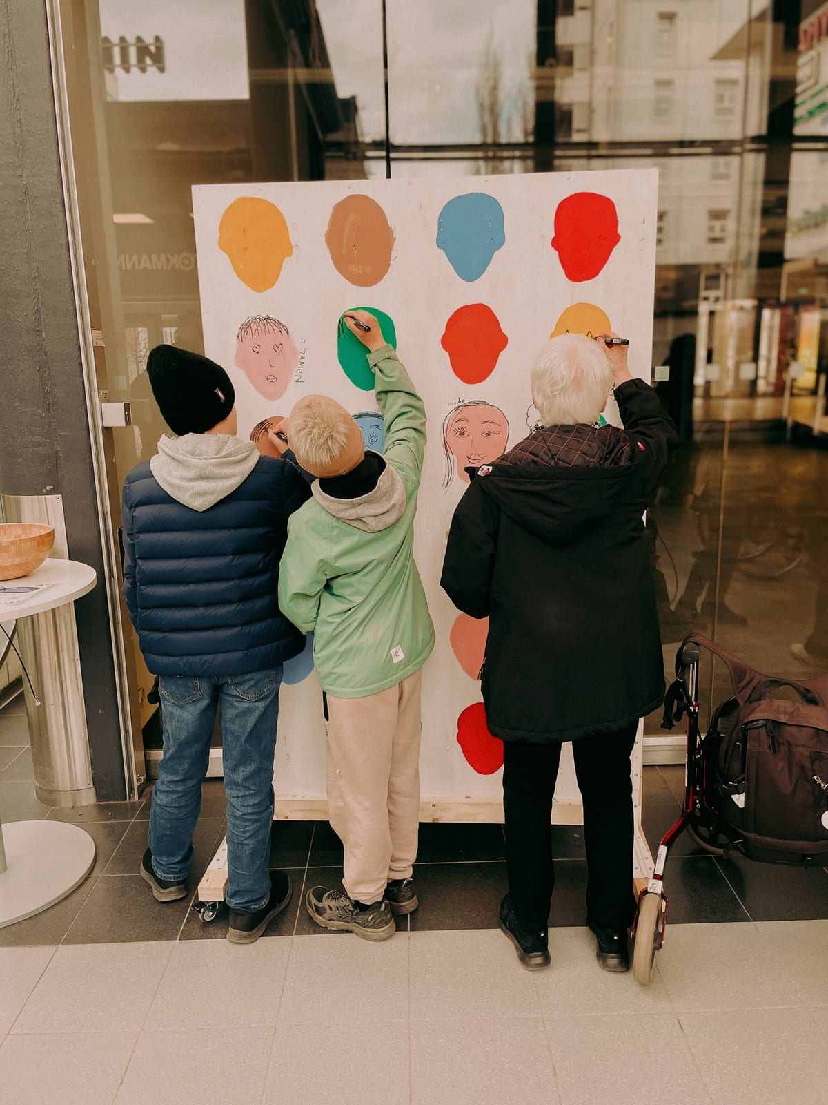 Children and an older person drawing together on a community artwork in Malmi